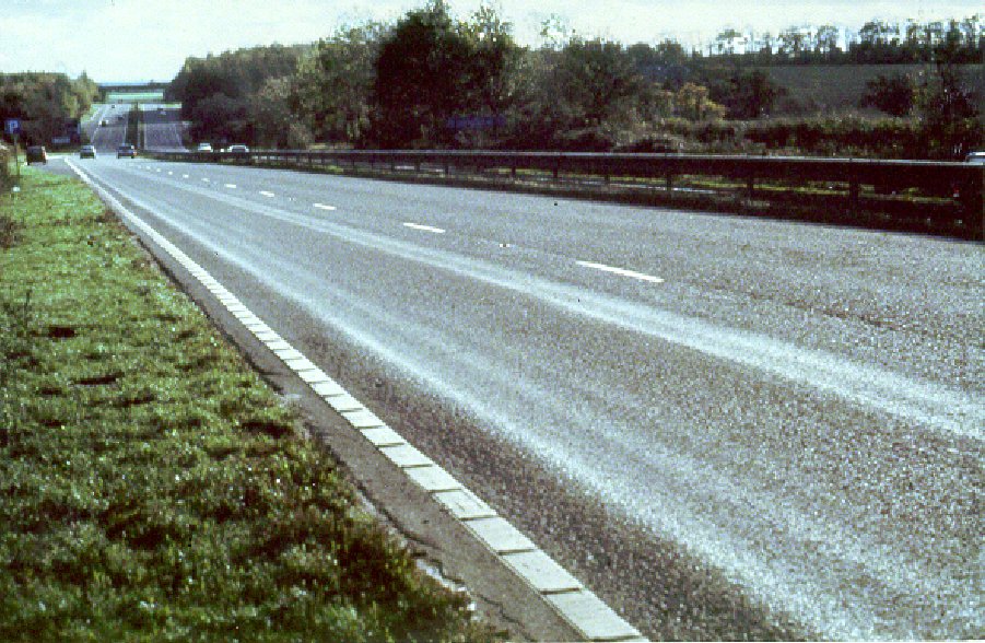 Photograph of an A-road in the UK, exhibiting wheel-path rutting (permanent deformation) due to heavy vehicles